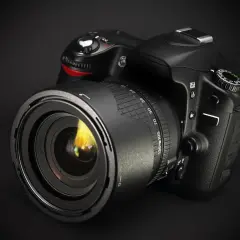 Czarny aparat Canon z obiektywem na ciemnym tle. Dowiedz się, jak sprawdzić przebieg aparatu Canon, aby ocenić jego stan.