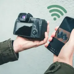 Bezprzewodowe przesyłanie zdjęć z aparatu do telefonu za pomocą SnapBridge po polsku. Widok z tyłu aparatu i ekran telefonu z podglądem.