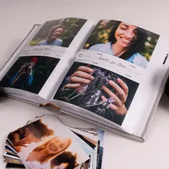 Otwarty album ze zdjęciami, aparat i stos fotografii. Idealny sposób, jak przechowywać zdjęcia i wspomnienia.