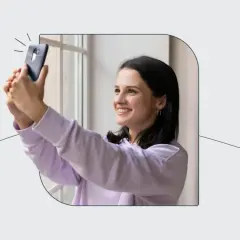 Uśmiechnięta dziewczyna robi selfie telefonem, zastanawiając się, ile zdjęć do dowodu będzie potrzebować.