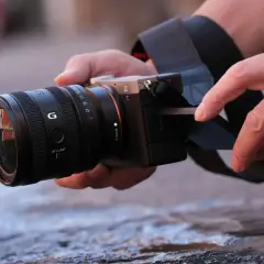 Dłonie trzymają aparat z obiektywem Sony G. To pokazuje, jaki obiektyw do czego – do tworzenia pięknych zdjęć.
