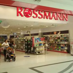 Wejście do drogerii Rossmann. Wózek z dzieckiem i dziewczynka przed półkami z kosmetykami. Cewe Rossmann cennik.