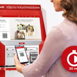 Kobieta używa smartfona z kodem QR do drukowania zdjęć na fotokiosku CEWE. Szybkie odbitki w 30 minut.