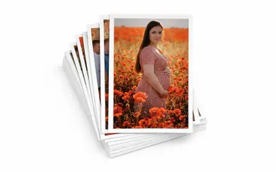Stos zdjęć formatu 13x18, na wierzchu ciężarna kobieta w sukience wśród maków.
