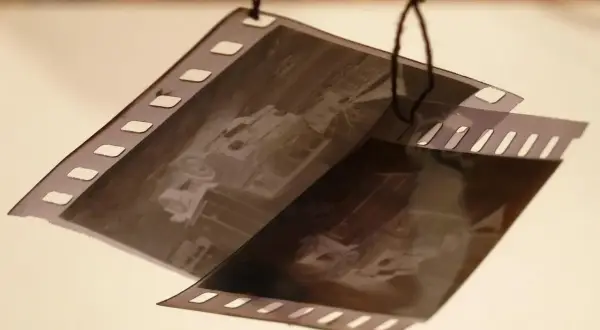 Klisze filmowe wiszą na sznurku, czekając na wywołanie. Zdjęcia przedstawiają stare samochody.