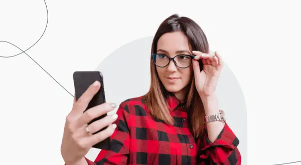 Kobieta w okularach robi sobie selfie telefonem. Czy zdjęcie do dowodu może być w okularach? Tak, jeśli nie zasłaniają twarzy.
